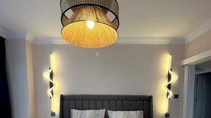 A modern bedroom with a large bed, a woven light fixture, and wall-mounted lighting. - Serene Stylish Central Cihangir Flat w/ Bosphorus 3-bedroom apartment (Beyoglu)