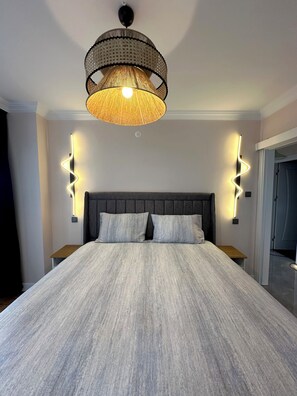 Ein modernes Schlafzimmer mit einem großen Bett, einer gewobenen Leuchte und Wandlampen.