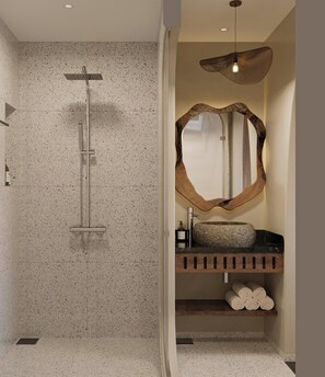 Ein Badezimmer mit einer freistehenden Dusche, einem großen Spiegel, einem Waschbecken mit Steinbecken und einem Holzboden mit Handtüchern.