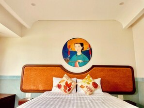 Ein Bett mit Kopfteil, Kissen mit floralen Mustern und einem runden Kunstwerk darüber.