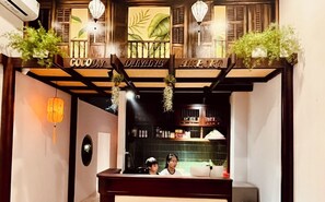 A traditional wooden entrance with hanging plants and a sign that reads 'COCOY DAMAGING ALL THE PORT.' - Cocoon Danang Airport Hotel & Apartment (Da Nang)