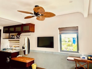 A compact kitchen with a ceiling fan, a TV, and a window with a view. - Cocoon Danang Airport Hotel & Apartment (Hoa Cuong)