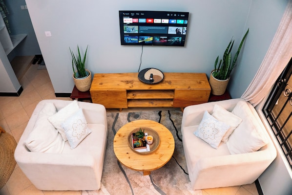 Una sala de estar con dos sofás, una mesa de centro, un televisor de pantalla plana y plantas en macetas.