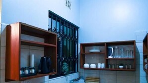 A compact kitchen with a toaster, kettle, and shelves with dishes. - Ilboru Haven Homes (Arusha)