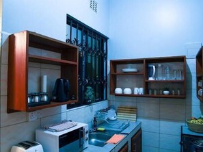 Una cocina compacta con tostadora, hervidor y estantes con vajilla.
