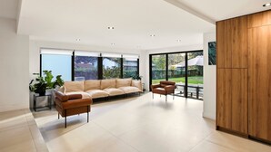 A modern living room with a sofa, chairs, a wooden cabinet, and large windows. - Superb Miami 4 Bedrooms, 3 Bath home, Perfect for Families & Groups (Miami)