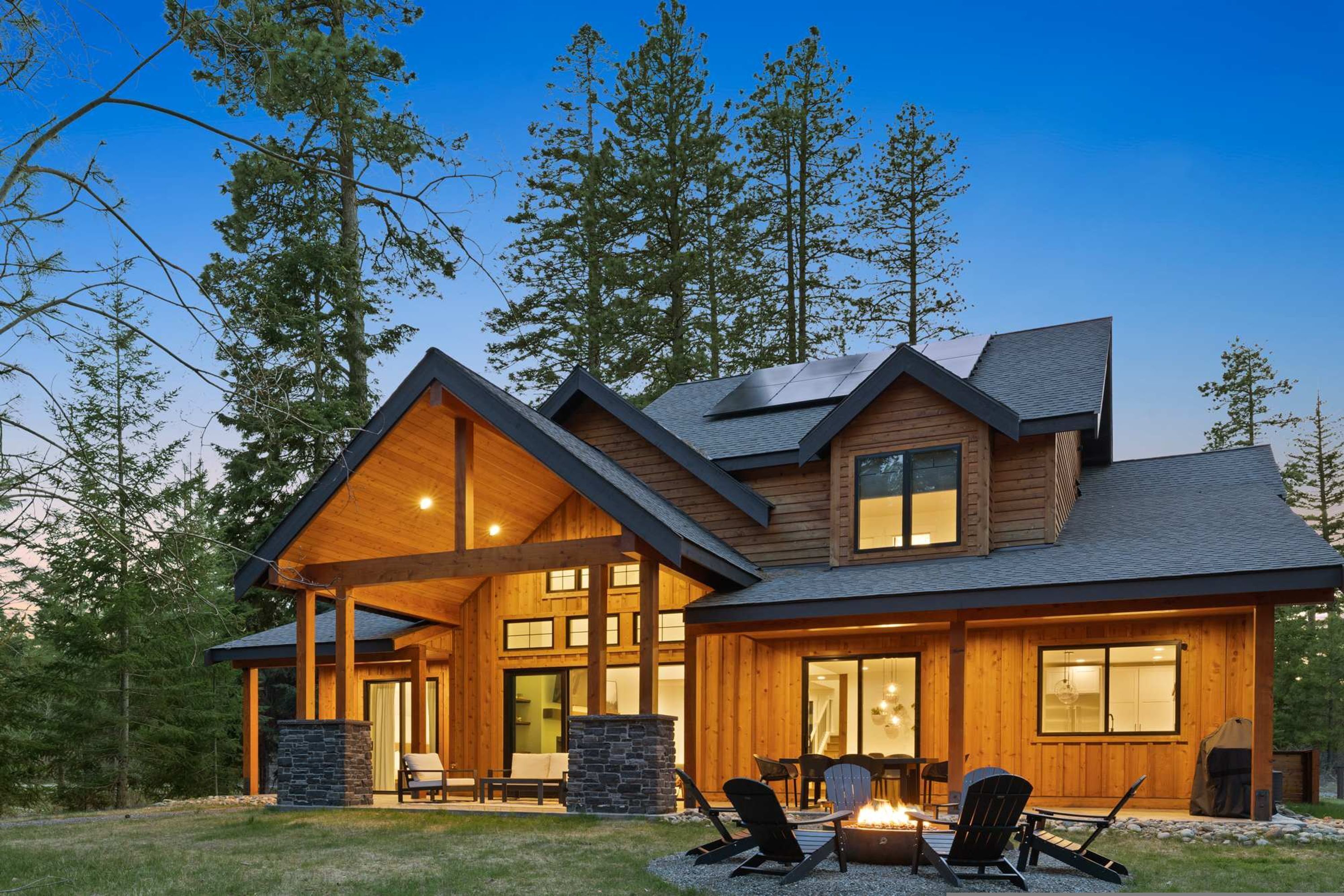 A log cabin with a covered patio, stone fireplace, and large windows.