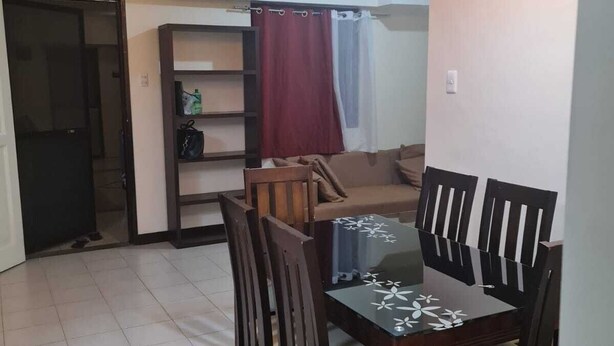 Un coin repas avec une table et des chaises, un canapé, une bibliothèque et une porte donnant sur une autre pièce.
