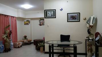 A living room with a glass-top table, a sofa, a small side table, and a decorative vase.