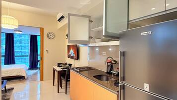 A modern kitchen with a built-in refrigerator, a dining area with a table and chairs, and a view of a cityscape through large windows.