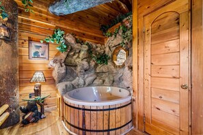 A wooden cabin interior with a hot tub, rustic decor, and a door. - Gatlinburg Enchanted Treehouse (Gatlinburg)