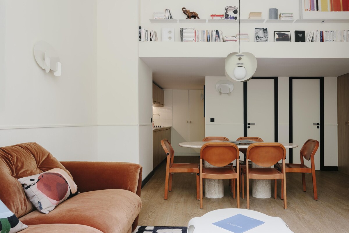 Ein moderner Wohnraum mit Sofa, Esstisch, Stühlen und Küchenzeile.