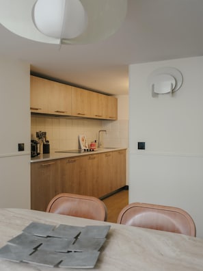 Eine moderne Küche mit Holzschränken, einer weißen Arbeitsplatte und einem Essbereich mit Tisch und Stühlen.