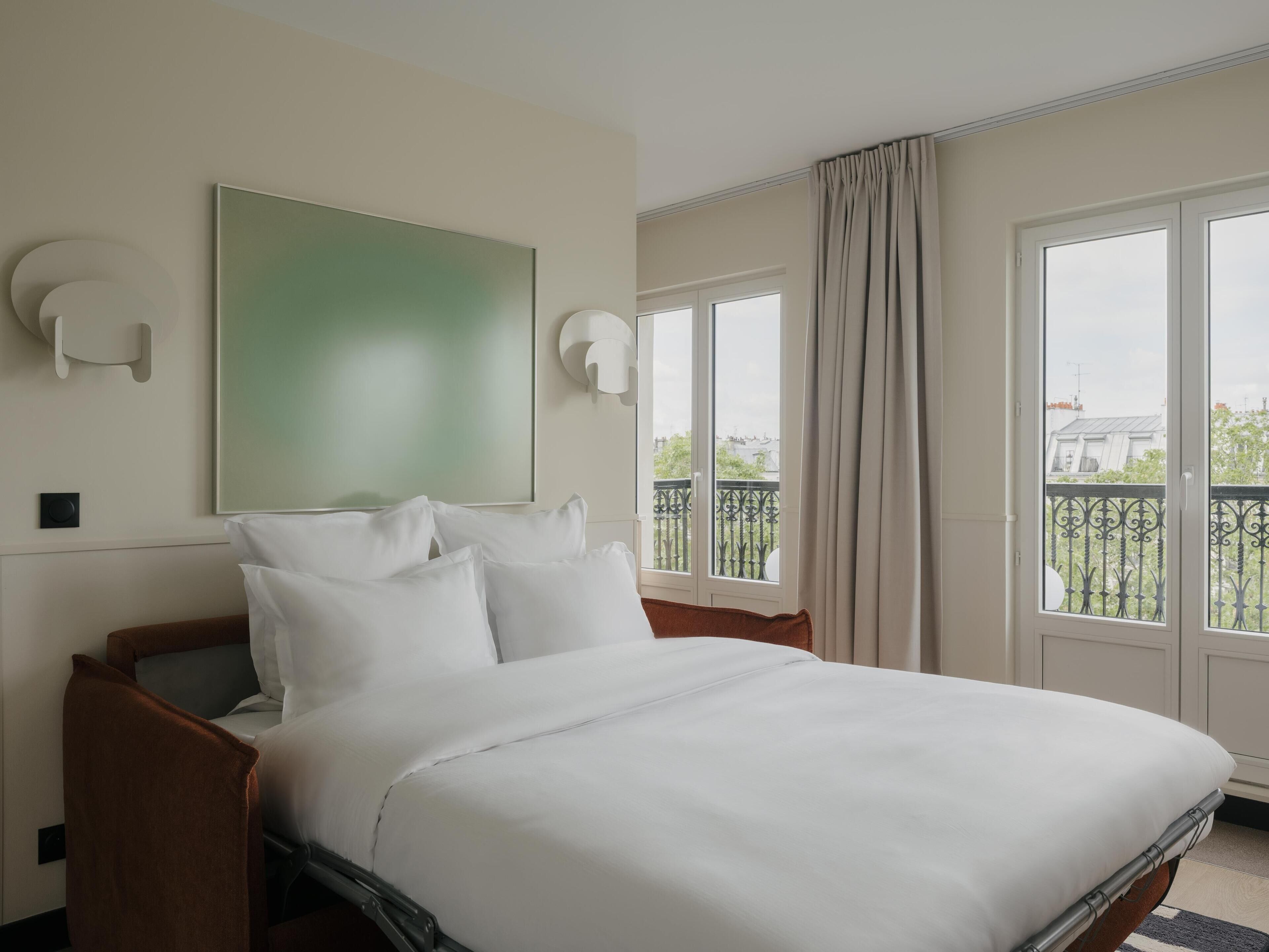 Une chambre d’hôtel avec un lit, une grande fenêtre et une vue sur la ville.