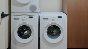 A laundry room with two stacked Bosch washing machines and a brown cabinet. - Edgar Suites - Jules Ferry (Paris)