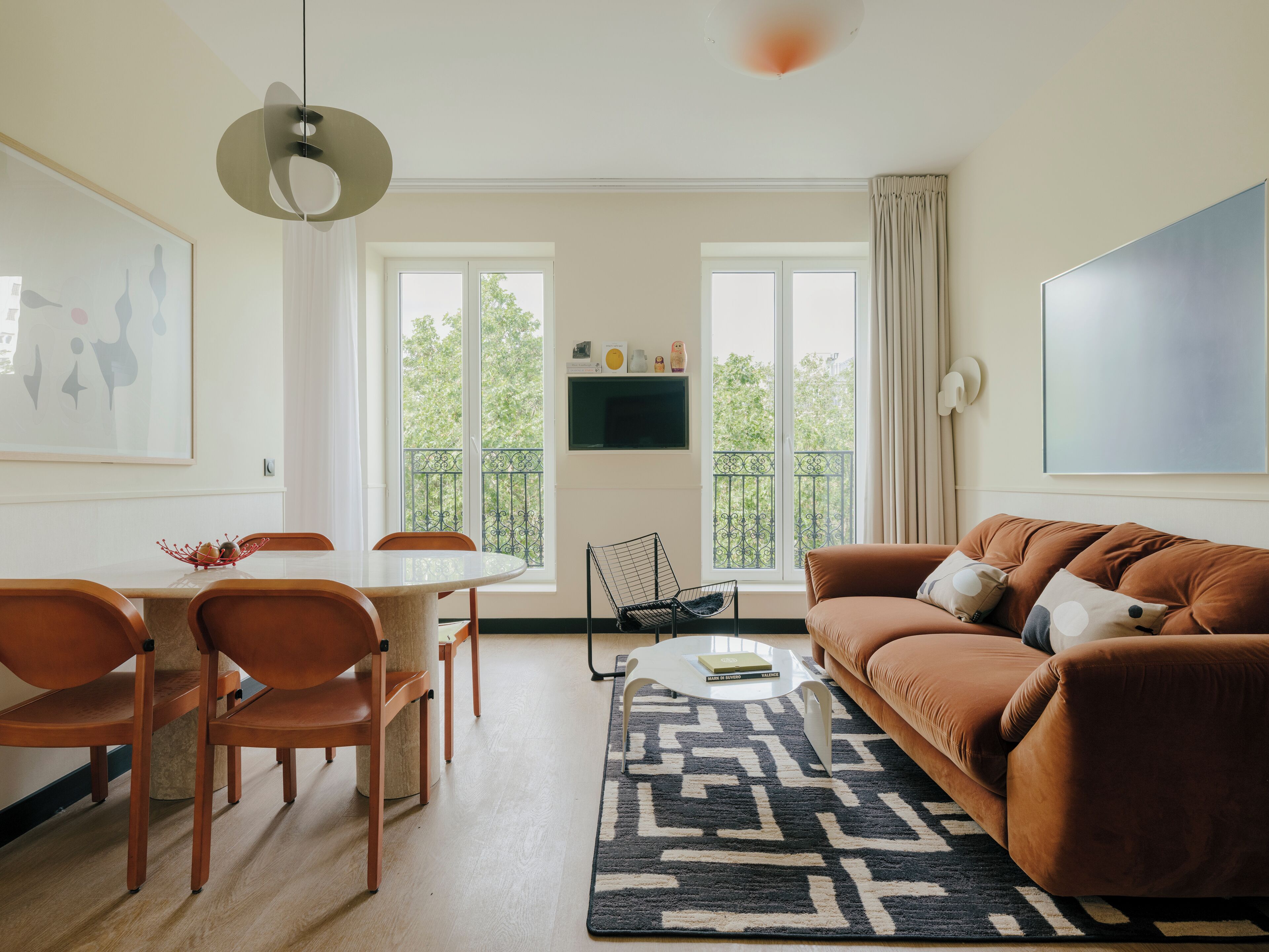 Ett modernt vardagsrum med en matplats, stora fönster, en soffa och ett soffbord.