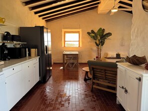 Eine Küche mit Kühlschrank, Kaffeemaschine und einem Esstisch mit Stühlen.