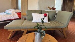 Ein Zimmer mit einer Couch, einem Bett, einem runden Holztisch und einer Topfpflanze.