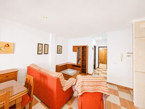 A room with a sofa, a small table, a cabinet, and a door leading to another room. - Apartamento San Jose bajo (Conil de la Frontera)