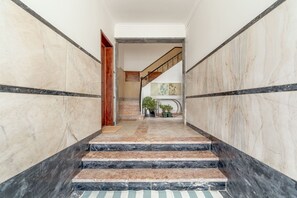 Uma escadaria de mármore com degraus alternados em preto e bege, conduzindo a um patamar.