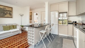 Una cocina moderna con una isla central, muebles blancos y un comedor con sillas.