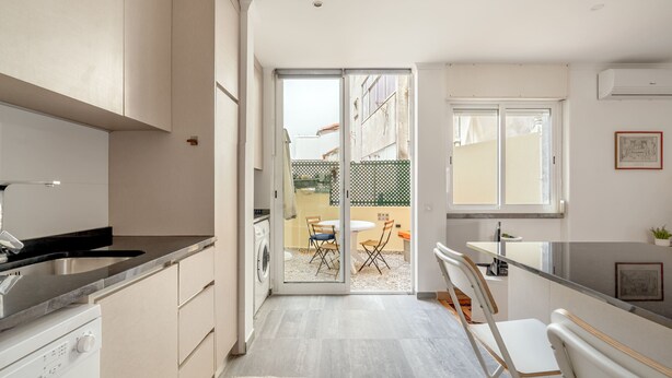 Una cocina moderna con lavavajillas integrado, un comedor con mesa y sillas, y una puerta corrediza de vidrio que da a un patio al aire libre.