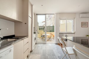 Una cocina moderna con lavavajillas integrado, un comedor con mesa y sillas, y una puerta corrediza de vidrio que da a un patio al aire libre.