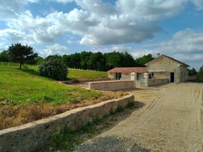 Une propriété rurale comprenant un bâtiment en pierre, une allée en gravier et un espace clôturé.