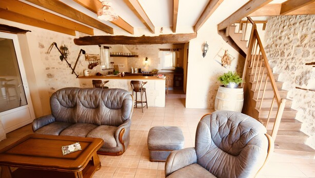 A cozy living room with leather sofas, a wooden coffee table, and a stone staircase.