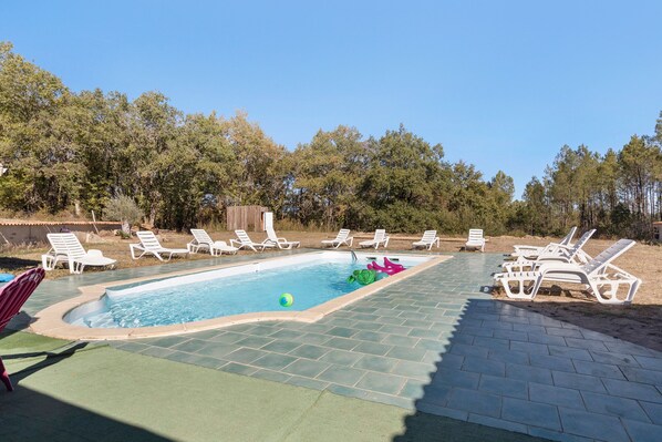 A swimming pool with lounge chairs and a hot tub area.