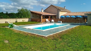 A house with a swimming pool, a wooden deck, and a covered patio area.