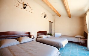 A hotel room with two beds, a wooden ceiling, and a radiator.