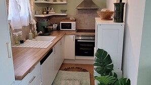 Een kleine keuken met een magnetron, oven en hanglamp.