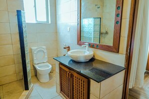 A bathroom with a toilet, sink, mirror, and shower. - Luxurious 5-bedroom Villa With Private Pool in Diani, Kenya (Diani Beach)