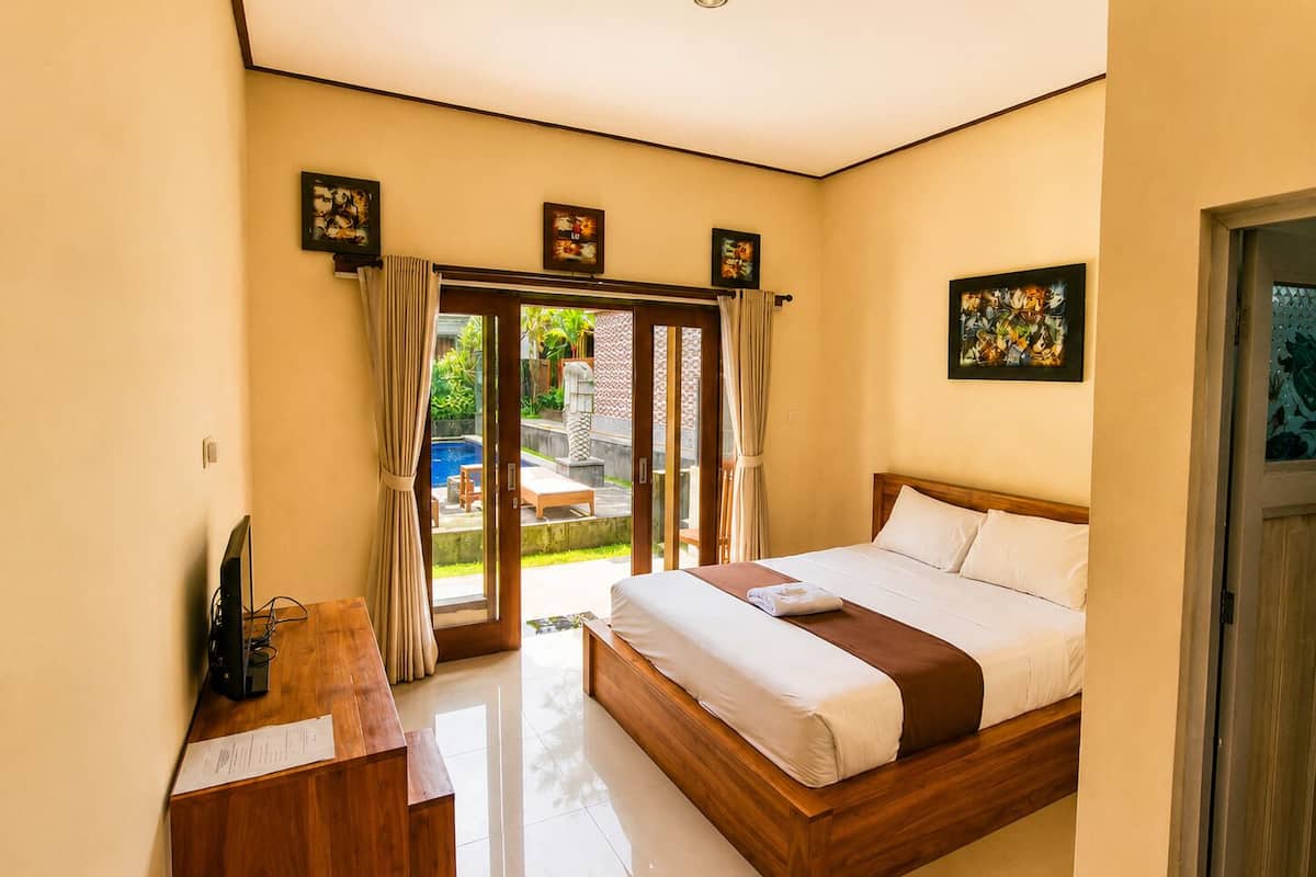 A bedroom with a bed, a desk, and a view of the outside.