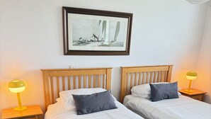 A double bed with white bedding, two bedside tables with lamps, a framed picture on the wall, and a wooden headboard. - Charming Coastal Retrest (Dunmore East)