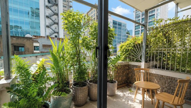 A balcony with potted plants, a table, and chairs. - Ben Thanh Hideaway - A Cozi Stay  (Ho Chi Minh City)