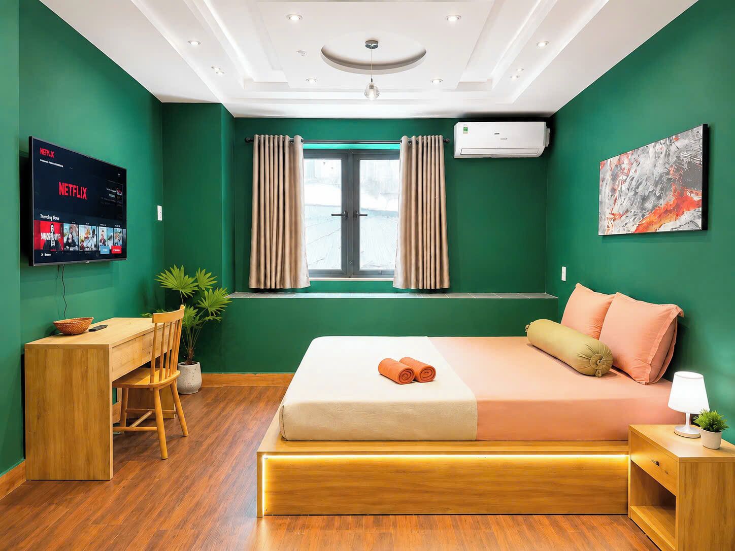 A modern hotel room with a bed, desk, and TV displaying Netflix.