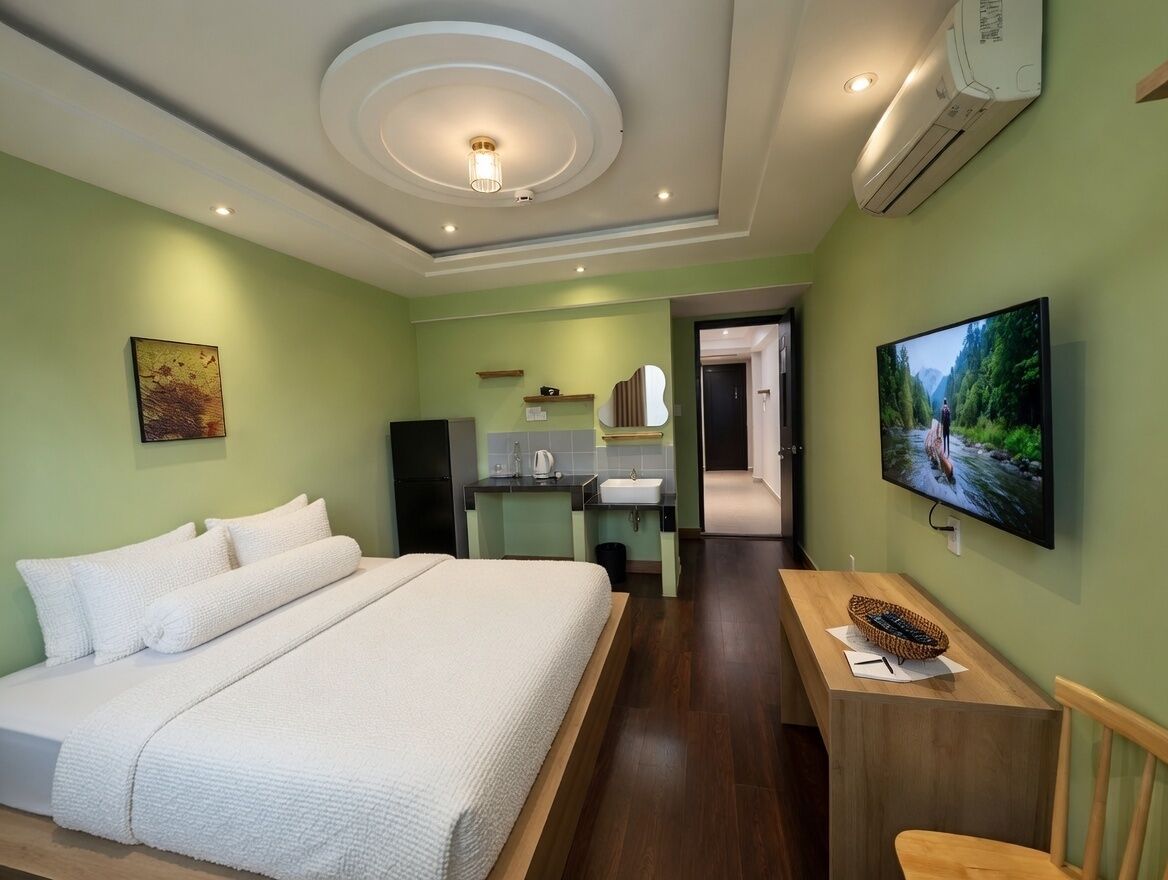 A hotel room with a bed, a desk, a TV, and a bathroom visible through an open door.