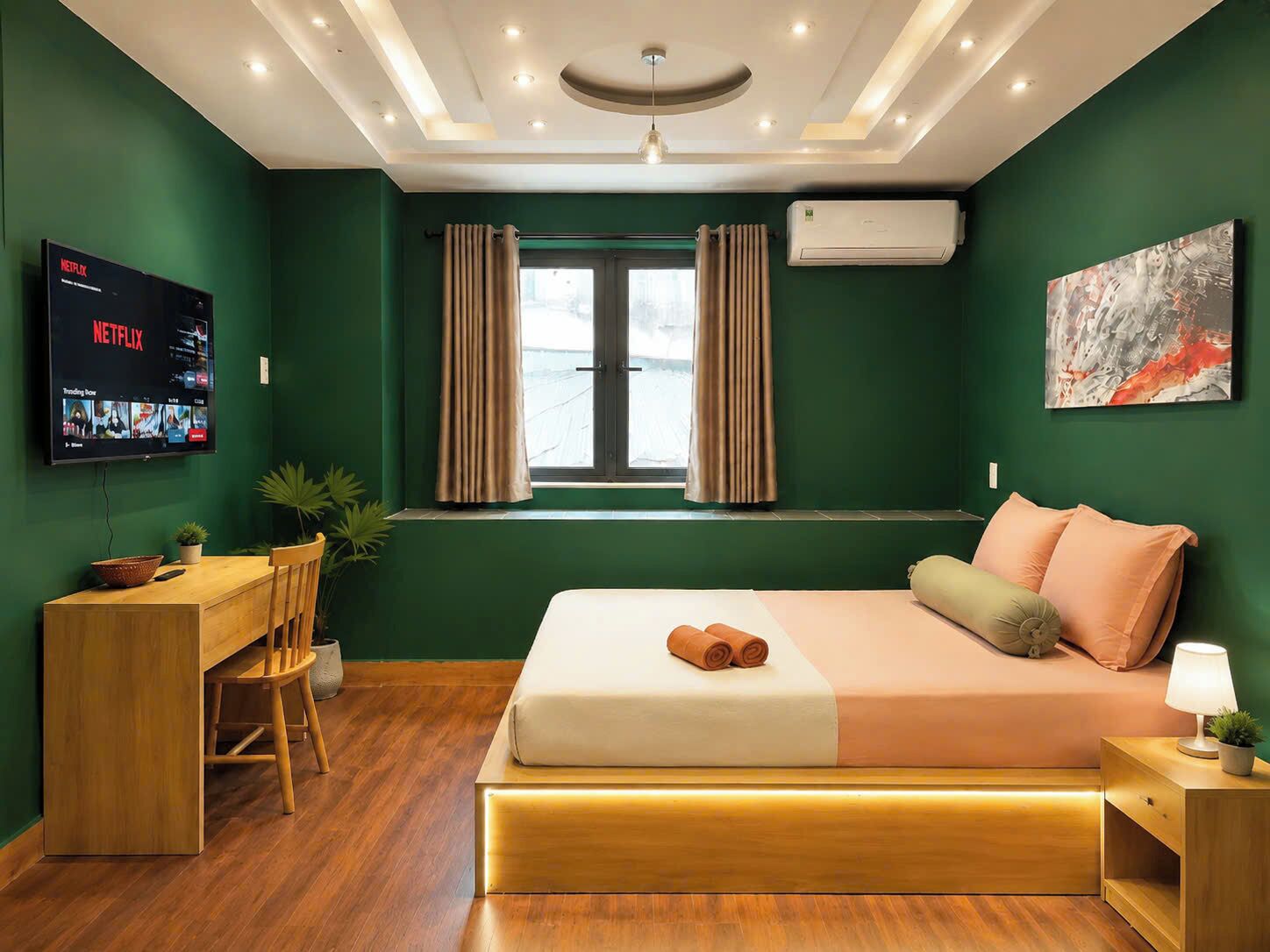 A modern hotel room with a bed, desk, and TV displaying Netflix.