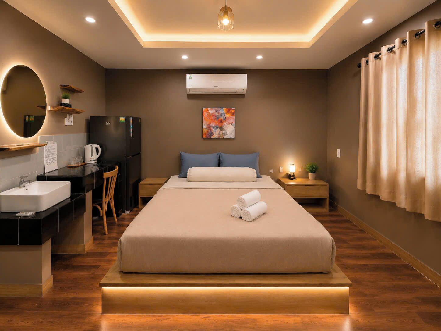 Ein modernes Hotelzimmer mit Bett, Nachttisch, Schreibtisch, Stuhl und einem großen Spiegel.
