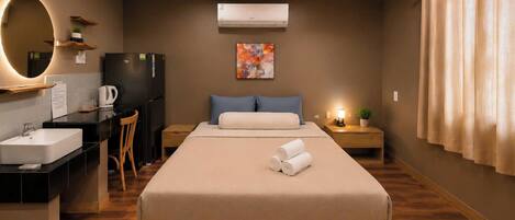 Ein modernes Hotelzimmer mit Bett, Nachttisch, Schreibtisch, Stuhl und einem großen Spiegel.