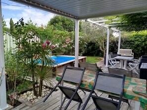 Ein überdachter Patio-Bereich mit Pool, Gartenmöbeln und üppiger Bepflanzung.