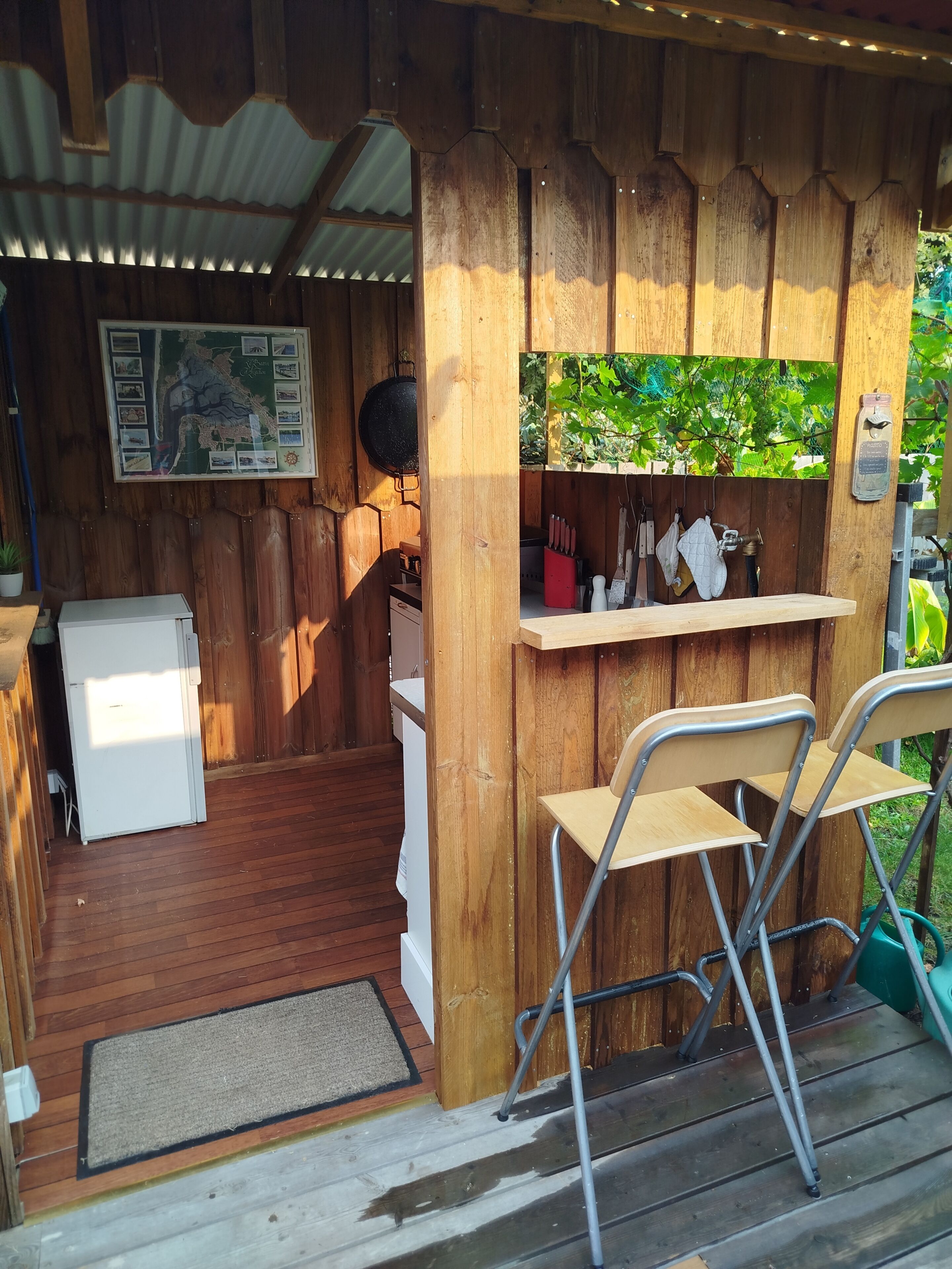 Eine Holzhütte mit Küchenbereich, inklusive Kühlschrank, Spüle und Ablagefläche für Küchenutensilien.