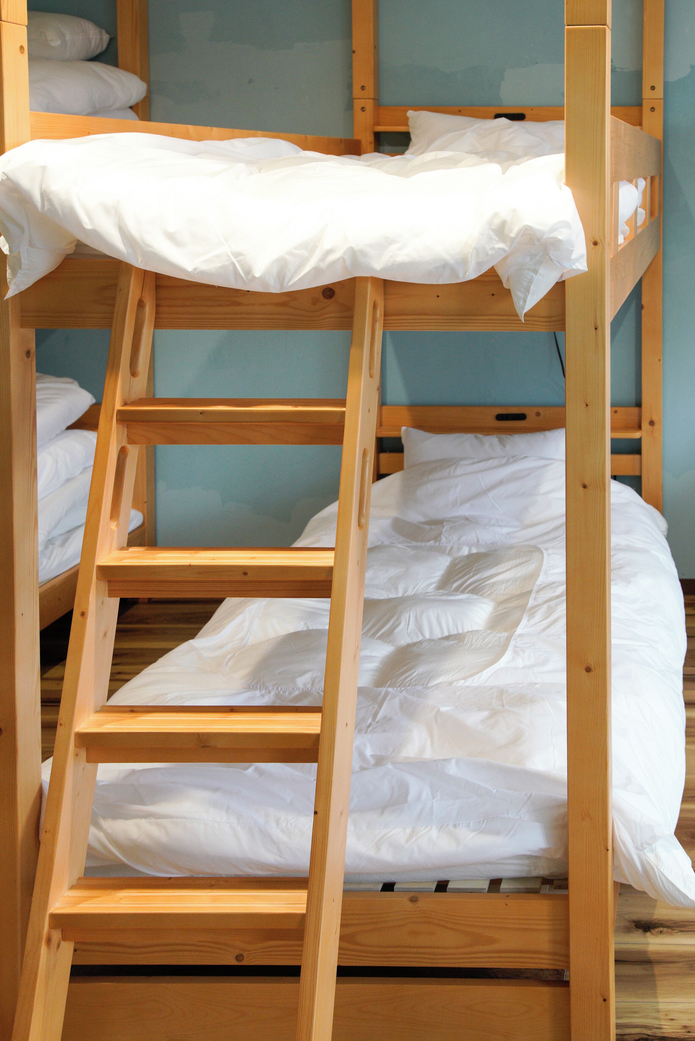 A bunk bed with white bedding and a wooden frame.