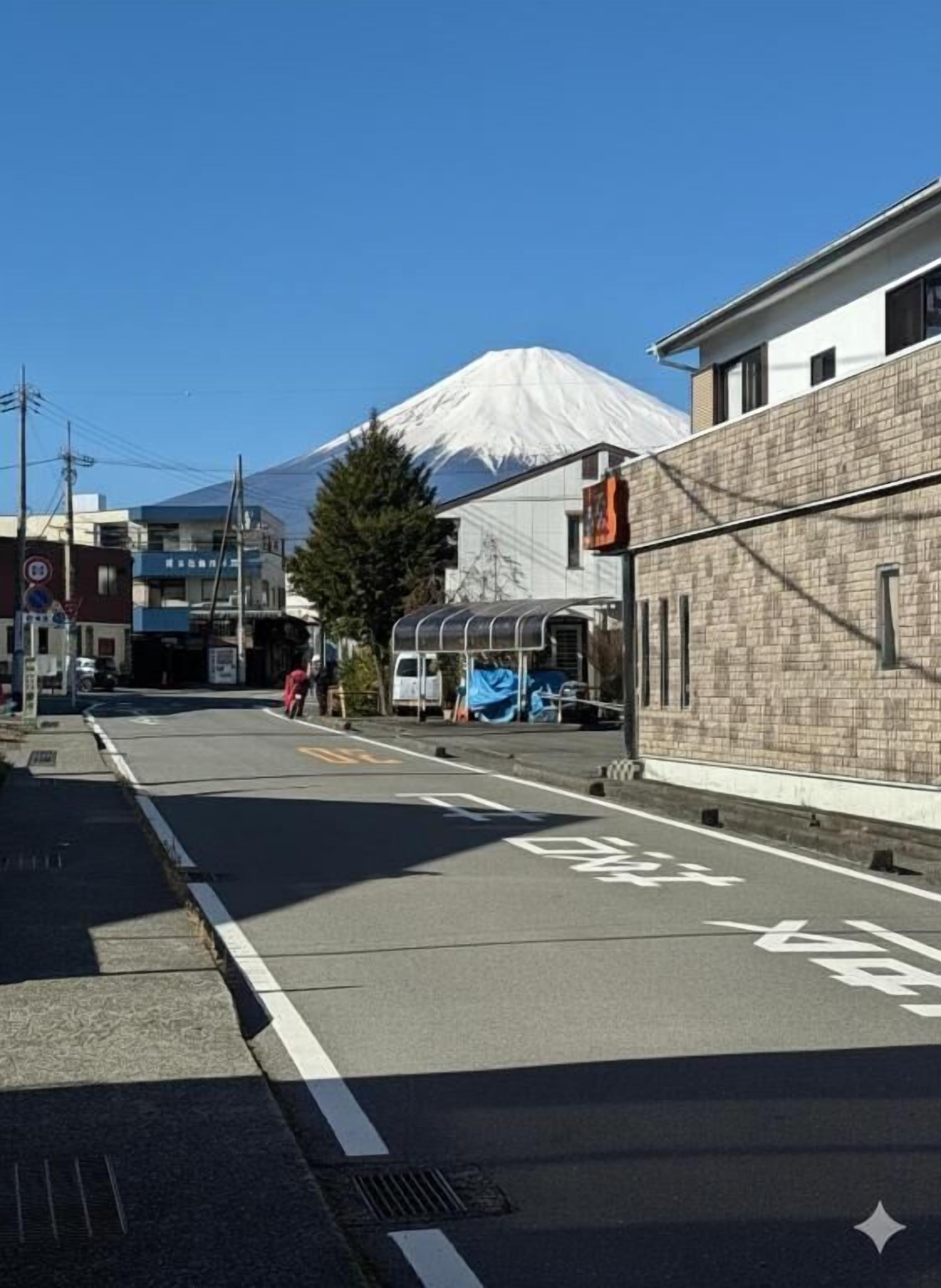 Una calle con una señal de tráfico, edificios y una montaña al fondo.