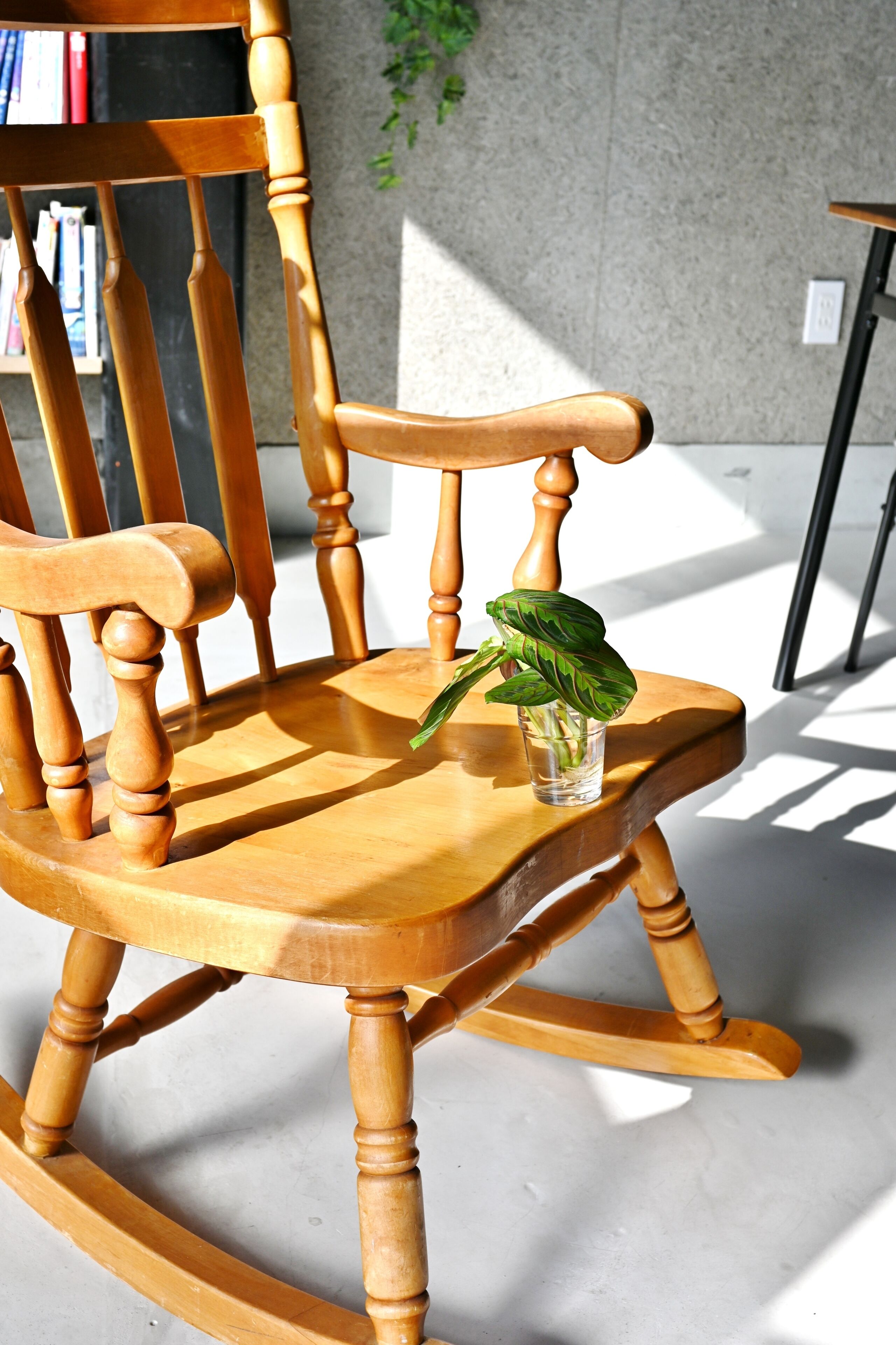 Een houten schommelstoel met een plant erop.