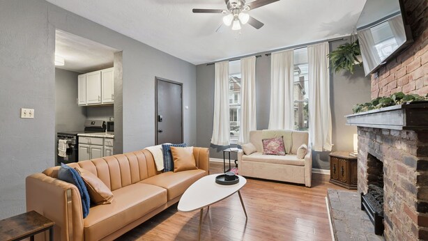 A living room with a sofa, a coffee table, a fireplace, and a television. - 2BR 1Bath 4 Beds Entire Apartment in Bloomfield (Pittsburgh)