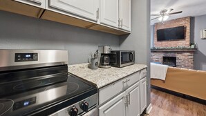 A kitchen with a stainless steel stove, microwave, and coffee maker on a granite countertop. - 2BR 1Bath 4 Beds Entire Apartment in Bloomfield (Pittsburgh)