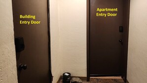 A building entry door and an apartment entry door with a textured wall and tiled floor. - 2BR 1Bath 4 Beds Entire Apartment in Bloomfield (Pittsburgh)